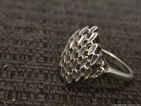 Oblique view of sterling silver ring showing scale-patterned dome