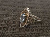 Side angle of sterling ring showing blue stone, filigree setting and band