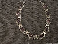 Front view of sterling silver necklace with eleven oval red cabochon stones