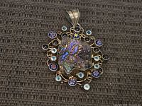 Front view showing druzy center, millefiori and blue stone accents, silver scroll frame and bail