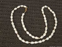 Full view of pearl necklace looped on dark background