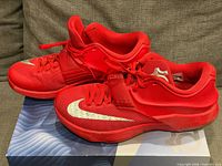 Side view of both red Nike KD VII sneakers on original box