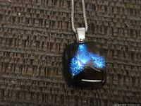 Close-up of pendant showing blue iridescent glass and silver bail