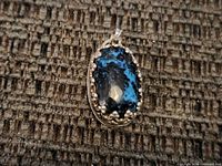 Front of pendant showing blue and black stone and silver bezel