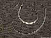 Full view of sterling silver herringbone necklace laid flat