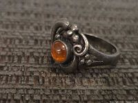 Front view of sterling silver ring showing orange cabochon and ornamental design