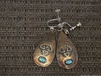 Front view of both earrings showing turquoise cabochons, stamped design, and screw-back findings