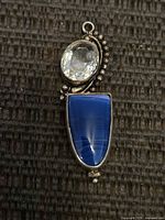 Front view of sterling pendant showing clear faceted stone and blue cabochon