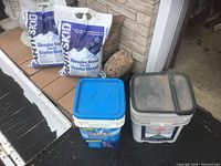 Two abrasive gravel bags and two ice melt pails in front of garage