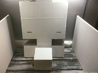 Stack of flat white cardboard boxes with one assembled example