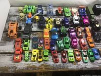 Full grouping of plastic toy cars, trucks and two small skulls on wooden surface