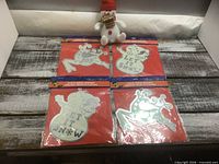 Four sealed mirror ornament packages and plush snowman group view