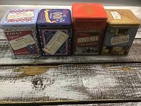 Front view of four Neilson Jersey Milk metal tins in a row