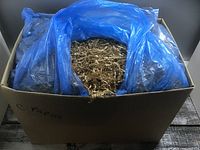 cardboard box filled with light brown crinkle paper lined with blue plastic bags