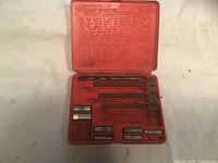 Open red case showing drill bits, extractors and guides with some empty slots