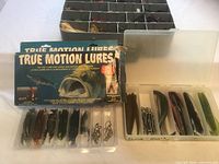 Overall view of tackle box, two open lids showing lures, True Motion Lures pack and smaller compartment with hooks