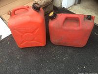 Front view of both red fuel containers on asphalt