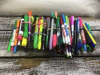 Three bundles of assorted coloured markers on wooden surface