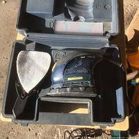 Open case showing sander, dust bag, sanding sheets