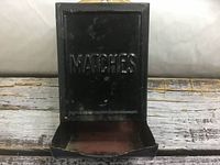 Front of black metal match holder with lid open, word MATCHES embossed
