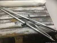 Two collapsed aluminum tripod legs with adjustment knobs