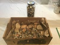 Box with mixed stones and nearby jar