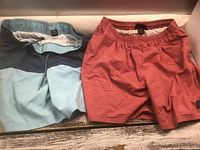 Blue and rose swim trunks side by side