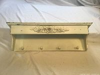 Front view showing entire shelf, floral motif, pegs