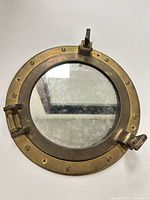 Front view of brass porthole mirror closed
