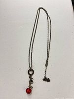 Full view of long chain necklace with apple charm and pendant ring