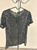 Front view of black lace short-sleeve top on hanger