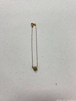 Full view of necklace laid flat showing bead pendant and clasp