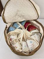 Top-down view of eight assorted teacups arranged in padded storage case