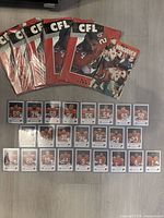 Lot overview showing five CFL Illustrated magazines, one Key to Vancouver magazine and complete BC Lions card set laid out on floor