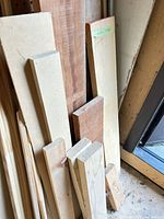 Stack of MDF strips, hardwood boards and pine boards leaning against wall