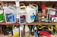 Shelved jugs, aerosols, boxed items and strap giving overview of lot contents