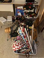 Overview of tote with wrapping paper rolls, gift bags, lights, wreath, tree stand