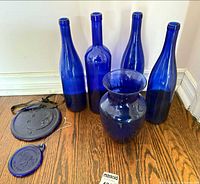 Group shot of all cobalt blue glass items: four bottles, vase, two suncatchers