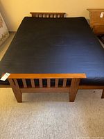 Full view of wooden futon bed frame with black mattress