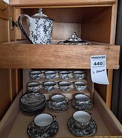 Overall view of tea set in cabinet showing teapot, sugar bowl, cups and saucers