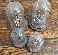Group view of four glass-domed military figurines