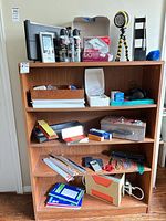 Full view of bookcase shelves showing majority of listed office supplies