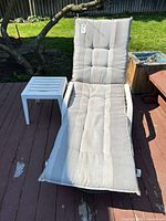 Chaise lounge with cushion and side table on deck