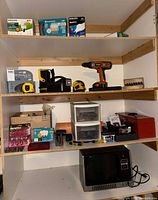 Full shelving unit with power tools, hand tools, light bulbs and TRS-80 monitor