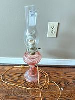 Full view of lamp showing pink glass base, clear chimney, cord