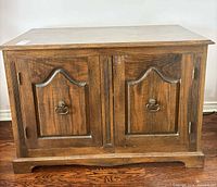 Front view of wooden media cabinet showing two doors and hardware