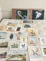Overview of assorted watercolours, sketches and two bird photographs displayed on mattress
