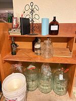 Shelving with glass carboys, plastic buckets, amber jugs, jar and other accessories