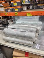 Stack of six semi-rigid aluminum ducts on shelf