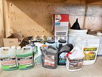 Group shot of assorted fluid containers including Shell DEF boxes, Optipath pail, shampoo jugs and spray bottles